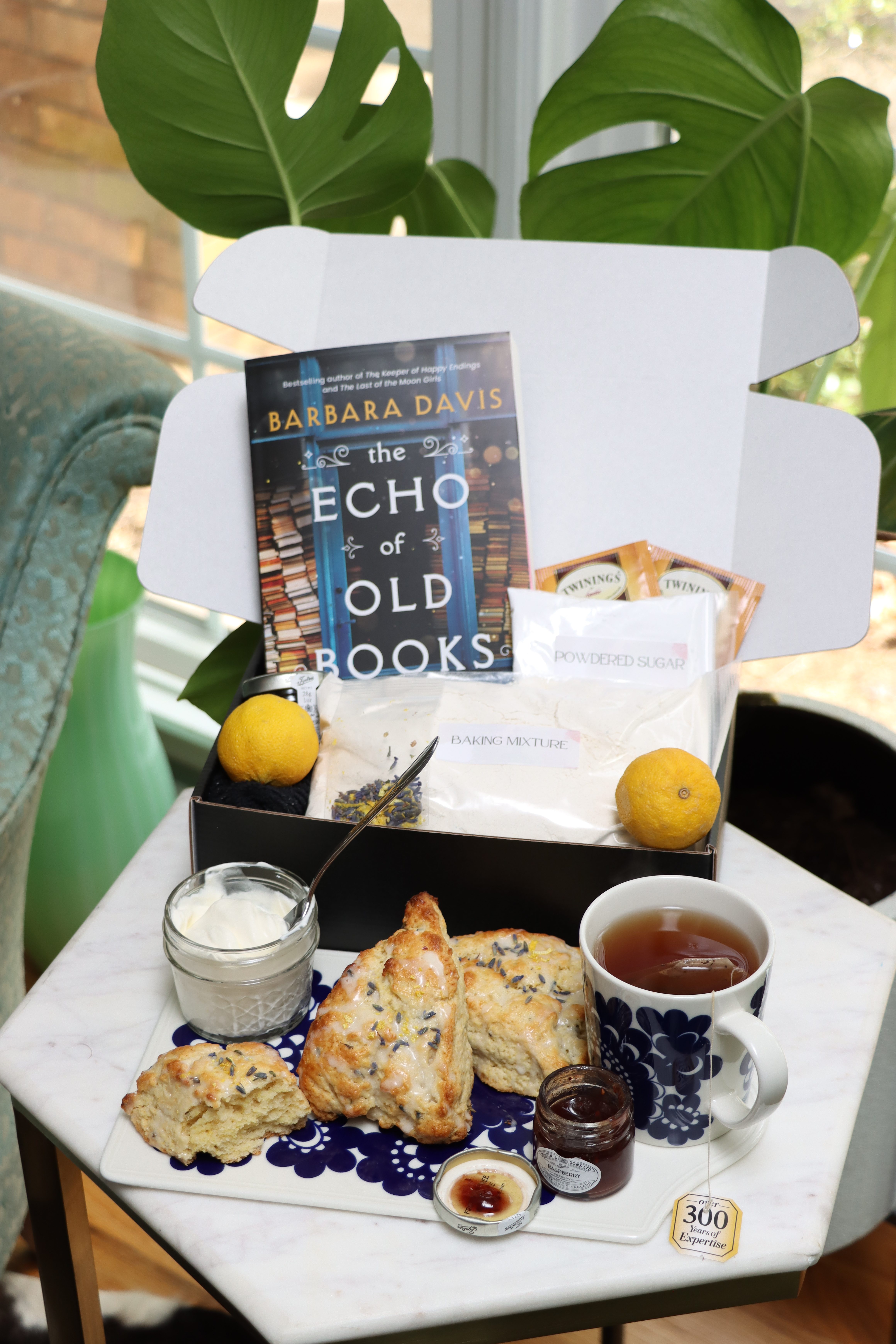 Open baking kit with lavender lemon scones, tea, and a book